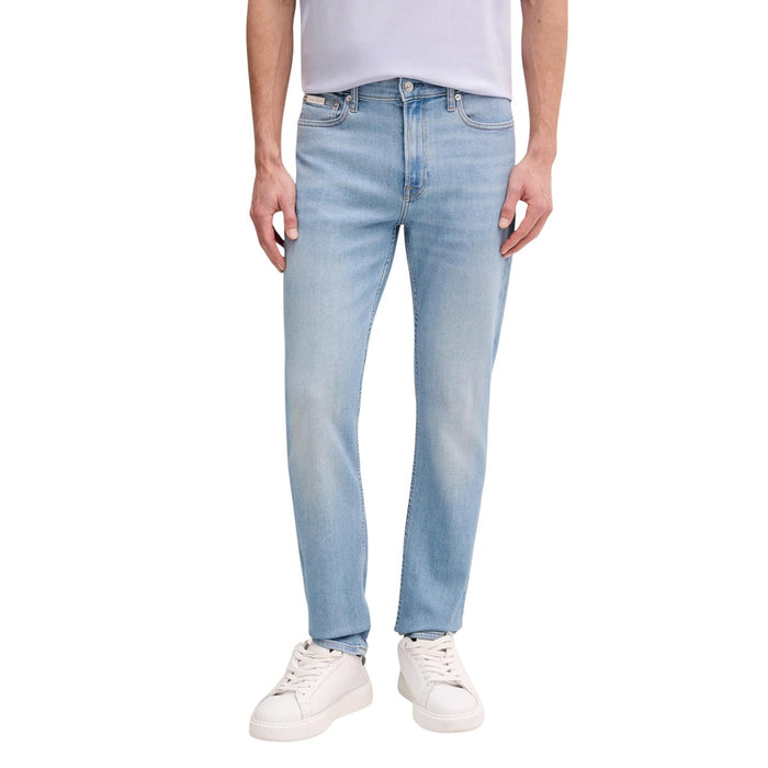 Image 1 : Jean droit Calvin Klein Jeans homme en denim bleu clair, coupe straight, porté avec un t-shirt lavande et des sneakers blanches — Delvale