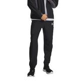 Pantalon technique Under Armour homme noir et gris porté de face avec veste assortie, coupe droite et chevilles resserrées