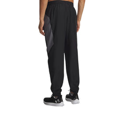 Pantalon technique Under Armour homme noir et gris porté de dos, insert contrasté gris sur les hanches, chevilles élastiquées