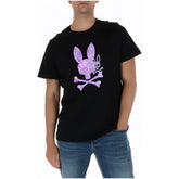 Image 1 : T-shirt Psycho Bunny homme noir avec logo skull lapin en impression camouflage rose et violet au centre, porté avec un jean bleu — Delvale