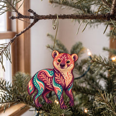 Laser-cut maple wood Bush Dog folk art ornament O364 hanging on a fir branch, made in USA