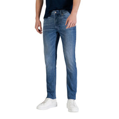 Image 1 : Jean slim Calvin Klein Jeans homme en denim délavé bleu moyen, porté avec t-shirt marine et sneakers blanches, vue de face — Delvale