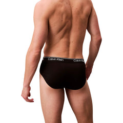 Image 3 : Détail gros plan de la ceinture jacquard Calvin Klein sur slip homme noir, répétition du logo blanc sur fond blanc épuré — Delvale