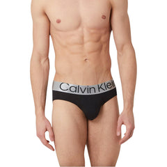 Image 1 : Slip homme Calvin Klein Underwear noir avec large ceinture élastique argentée frappée du logo, porté par un mannequin masculin — Delvale