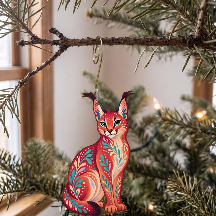 Laser-cut maple wood Caracal folk art ornament O352 hanging on a fir branch, made in USA