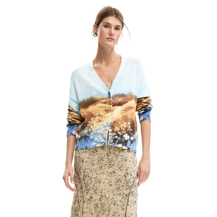 Image 1 : Femme portant le cardigan Desigual à imprimé paysage aquarelle bleu azur et caramel, col en V et boutons dorés, associé à une jupe longue fleurie — Delvale