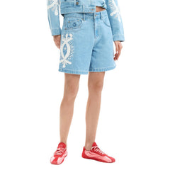 Image 1 : Short denim femme Desigual bleu clair avec broderies florales blanches sur la jambe, porté avec une veste en denim assortie et des baskets rouges — Delvale