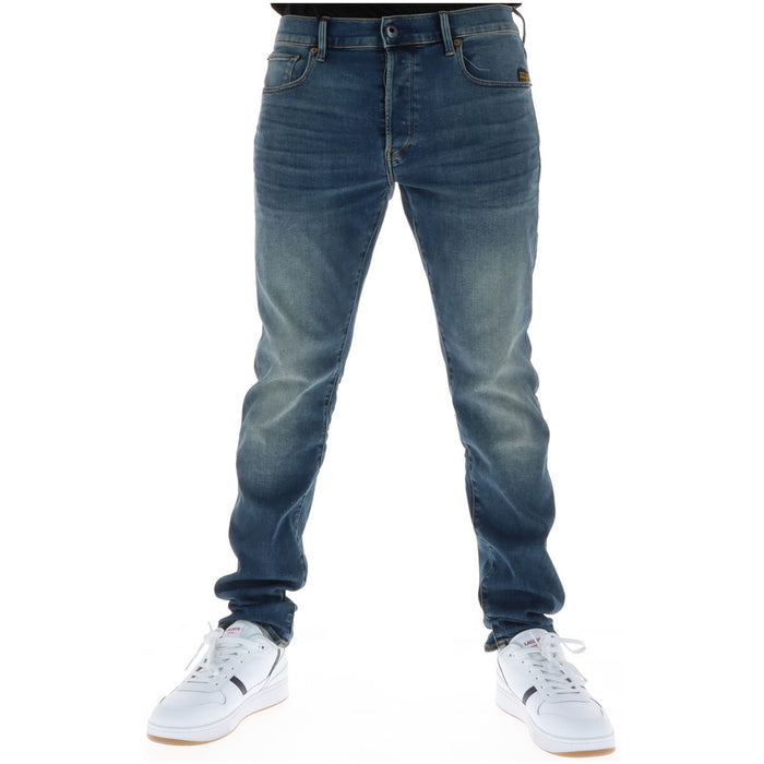 Image 1 : Jean slim G-Star homme en denim bleu effet usé porté avec des sneakers blanches Lacoste, vue frontale — Delvale