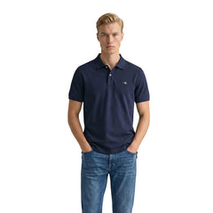 Image 1 : Homme portant le polo piqué Gant Shield bleu marine à manches courtes avec un jean brut, vue de face — Delvale