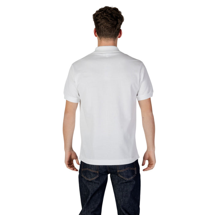 Image 2 : Vue de face du polo Lacoste homme blanc en coton piqué, col polo et fermeture boutons visible, porté sur jean foncé — Delvale