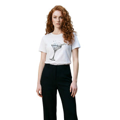 Image 1 : Femme rousse portant un t-shirt Liu Jo blanc à manches courtes avec imprimé verre à cocktail graphique noir et argent, associé à un pantalon noir — Delvale