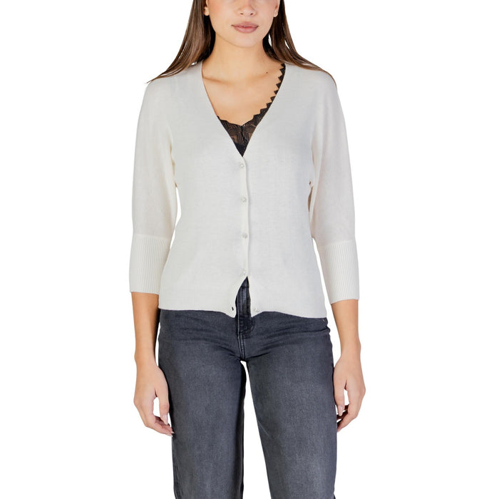 Image 1 : Femme portant un cardigan Morgan De Toi blanc crème col V avec boutons nacrés et manches trois-quarts, porté sur un top en dentelle noire avec un jean gris — Delvale