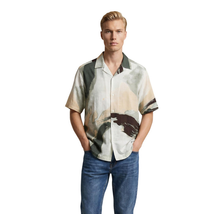 Image 1 : Homme portant la chemise manches courtes Only & Sons à imprimé aquarelle kaki et sable, col classique ouvert, avec un jean brut — Delvale