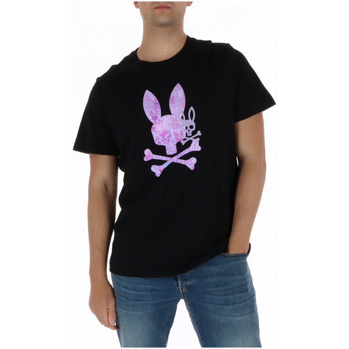 Image 1 : T-shirt Psycho Bunny homme noir avec logo skull lapin en impression camouflage rose et violet au centre, porté avec un jean bleu — Delvale