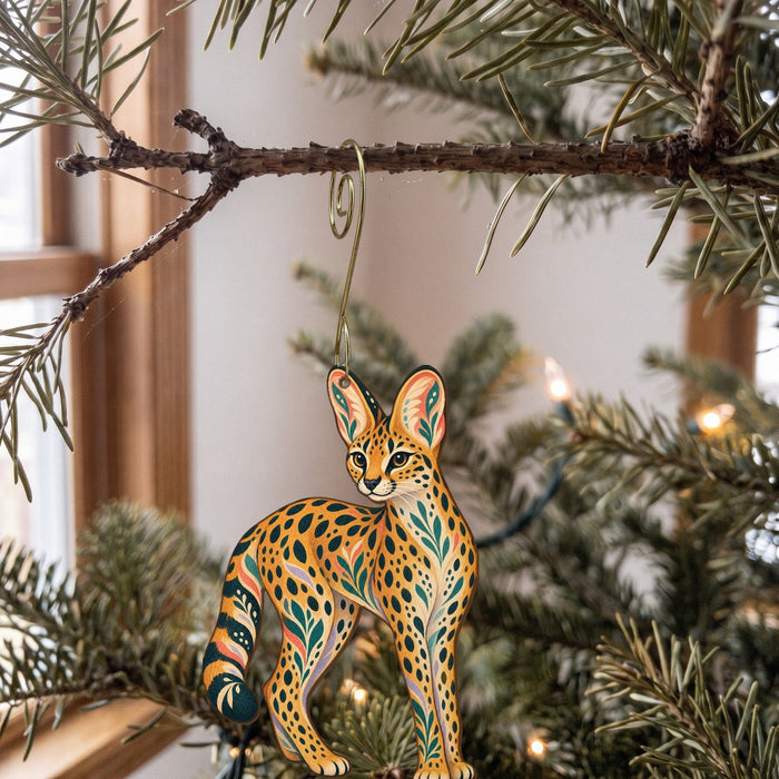Laser-cut maple wood Serval folk art ornament O351 hanging on a fir branch, made in USA