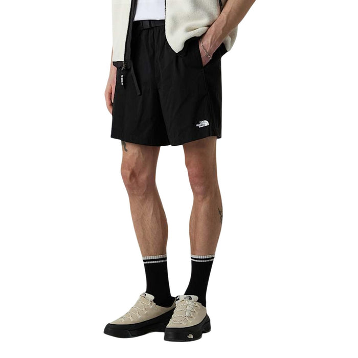 Image 1 : Bermuda homme The North Face noir porté de profil, avec logo brodé sur la cuisse, ceinture élastiquée et poches frontales — Delvale